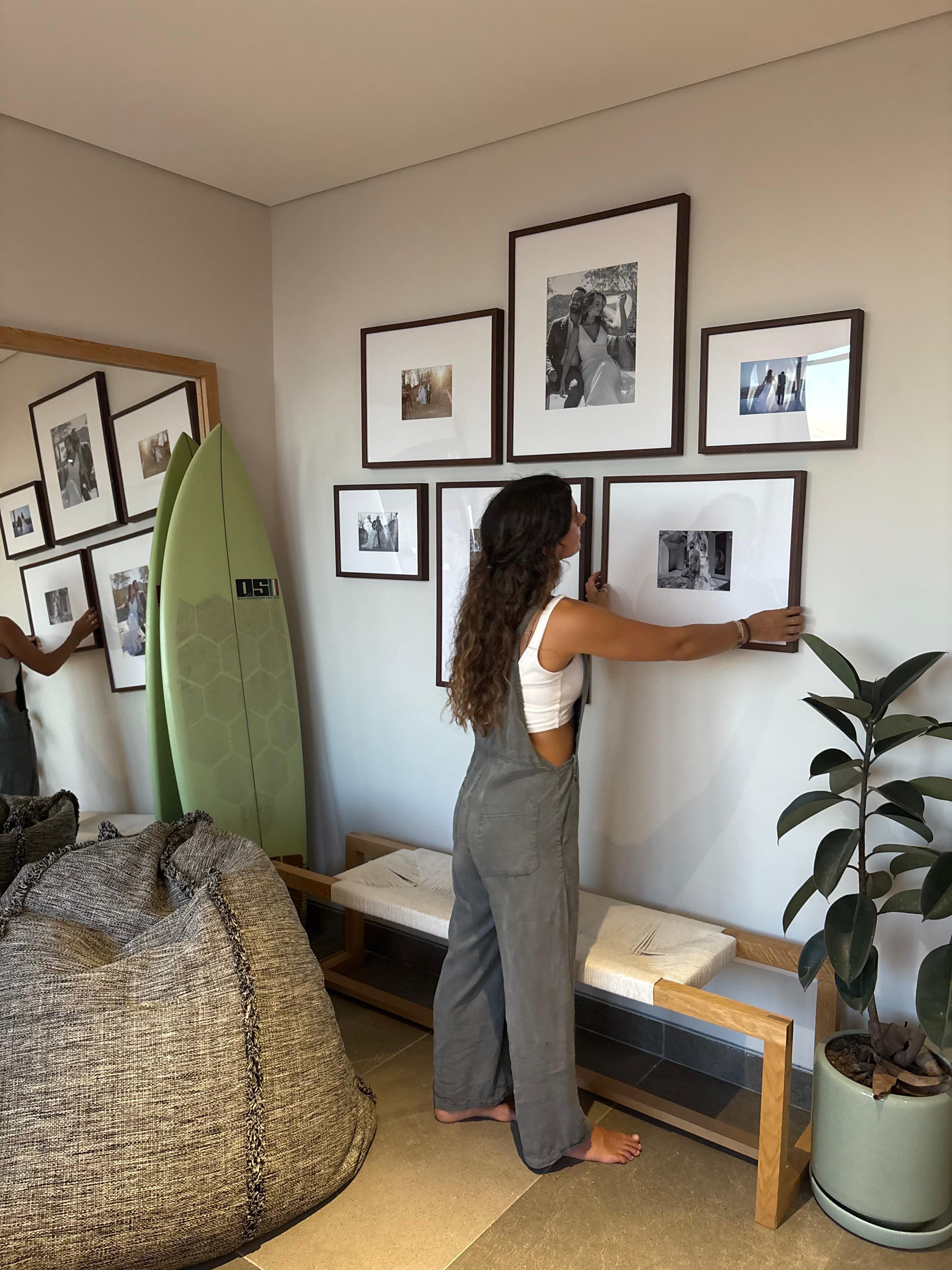 Mujer colgando una galería de marcos Pictoset con fotos de boda en la pared
