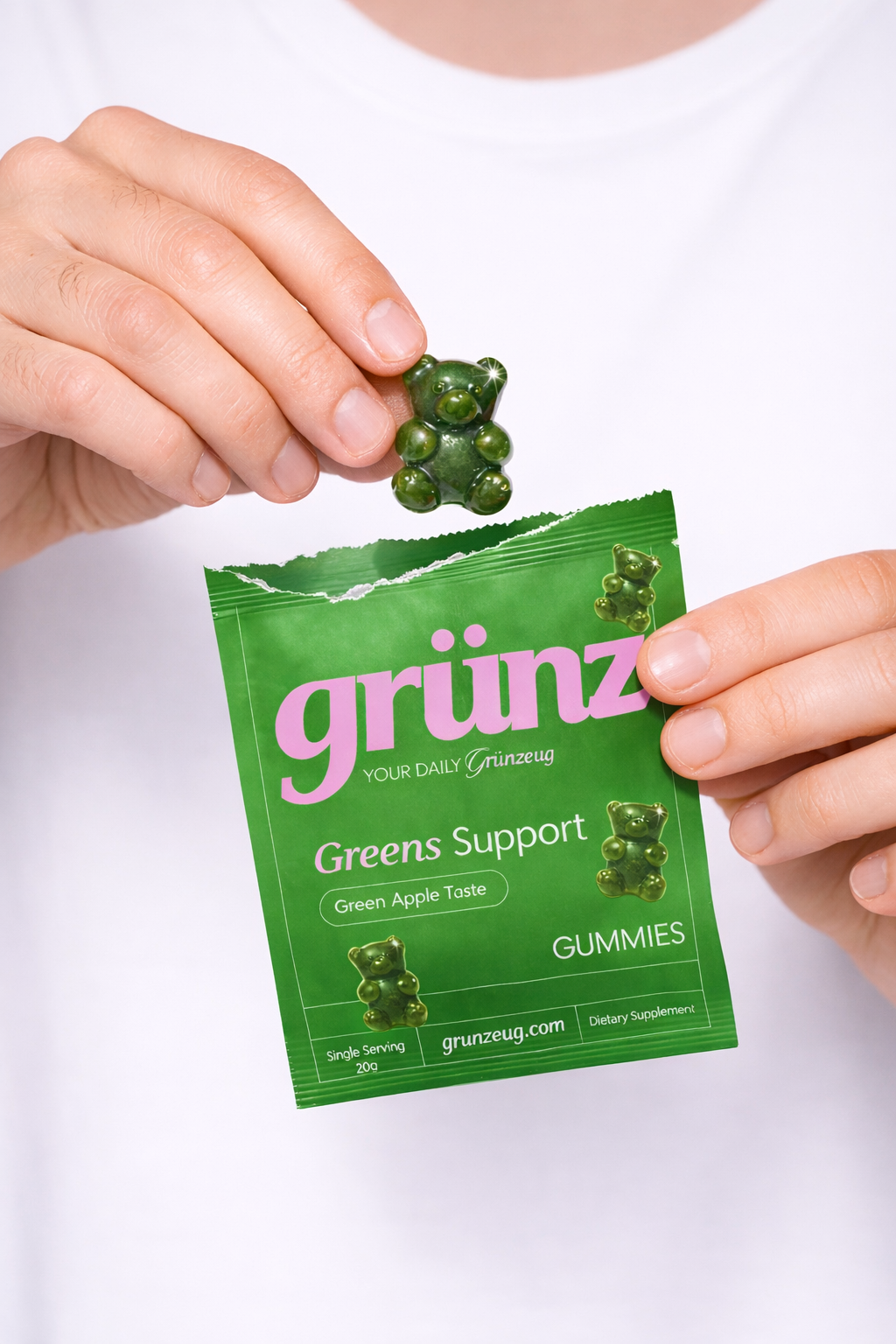 Hands holding a green package labeled grünz and a green bear-shaped gummy candy