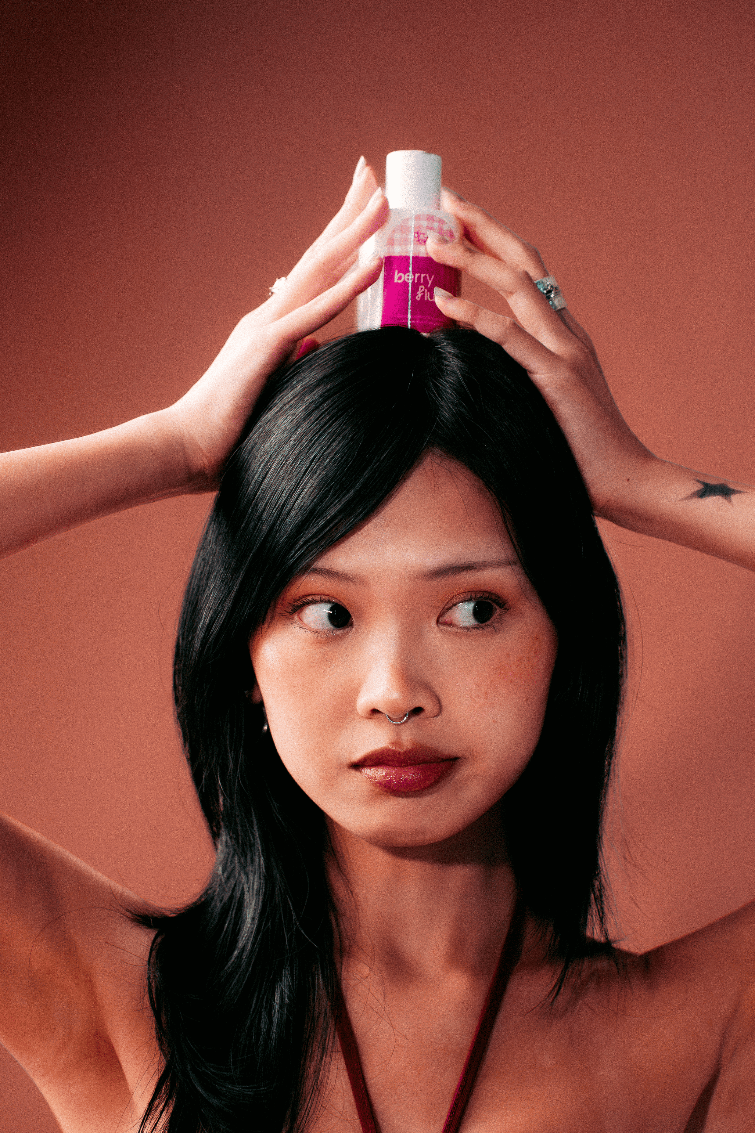 Woman holding a Berry Flush hair perfume on top of her head