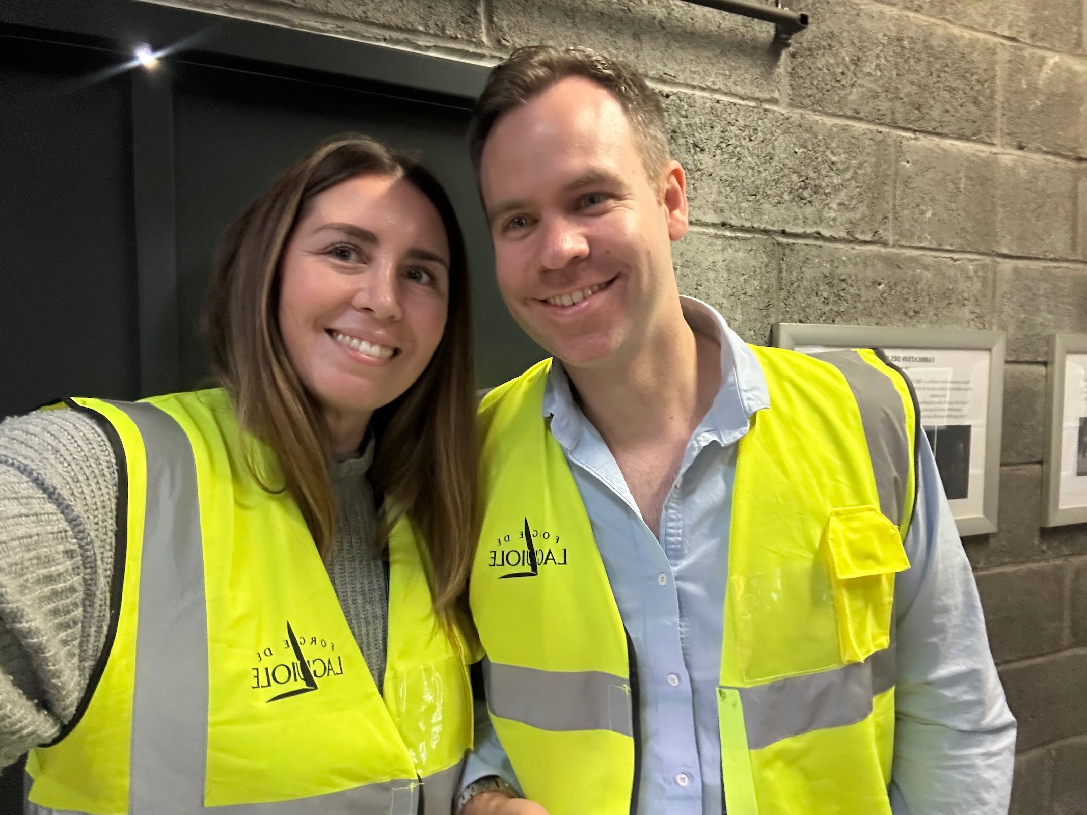 Rachel and Tobias smiling in Forge de Laguiole high-visibility vests during a visit to the Forge de Laguiole factory in France