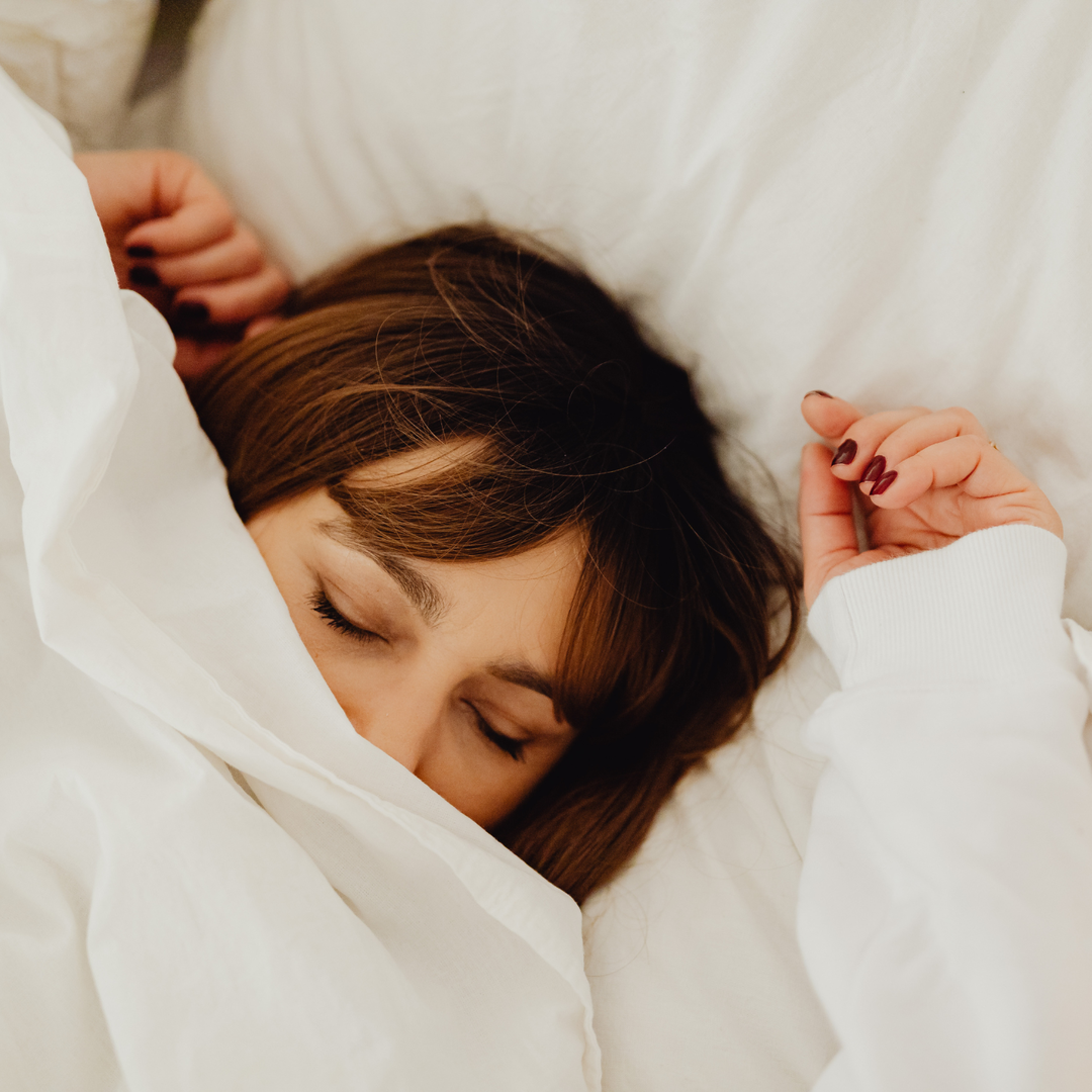 Femme dormant paisiblement sous une couette blanche