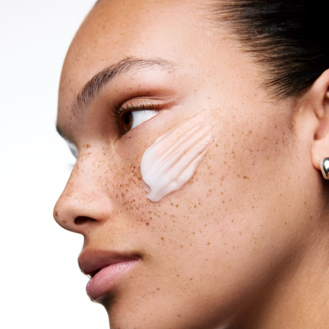 Femme appliquant une crème hydratante sur la joue