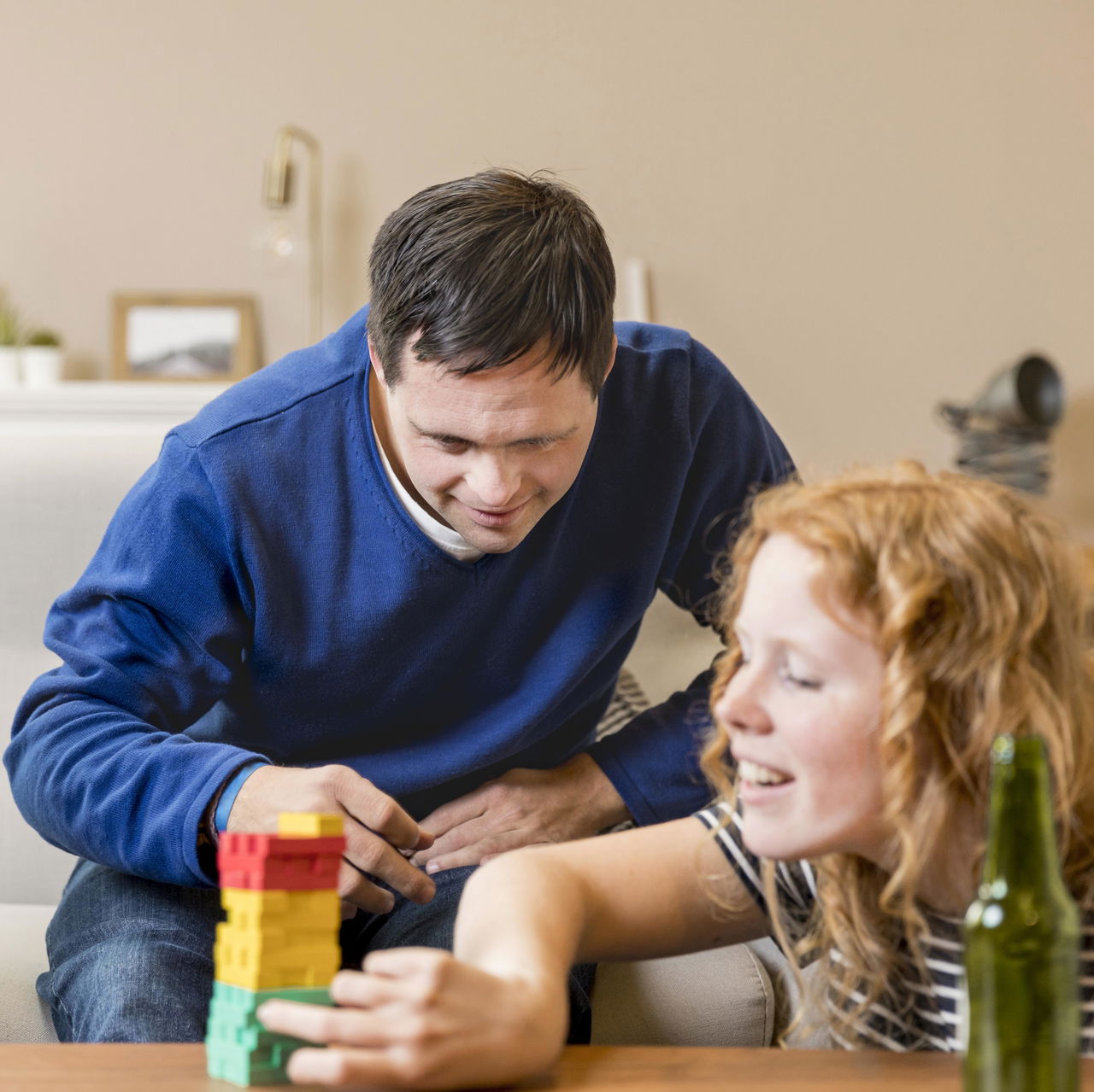 Man and woman sitting on a couch playing with colorful building blocks on a table
