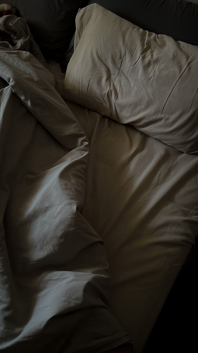 A dark, rumpled bed in the middle of the night