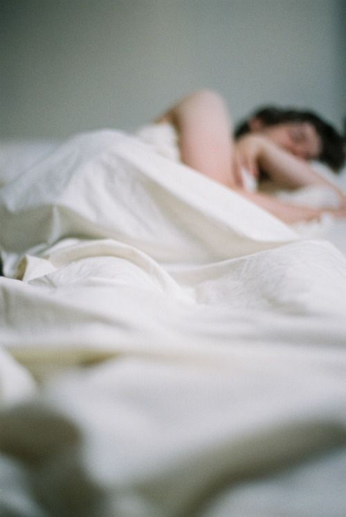 A woman sleeping soundly under crisp white sheets