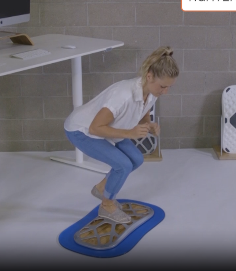 Squat and reach standing desk exercise on a FluidStance balance board, from Pop-Up Workout Episode 3