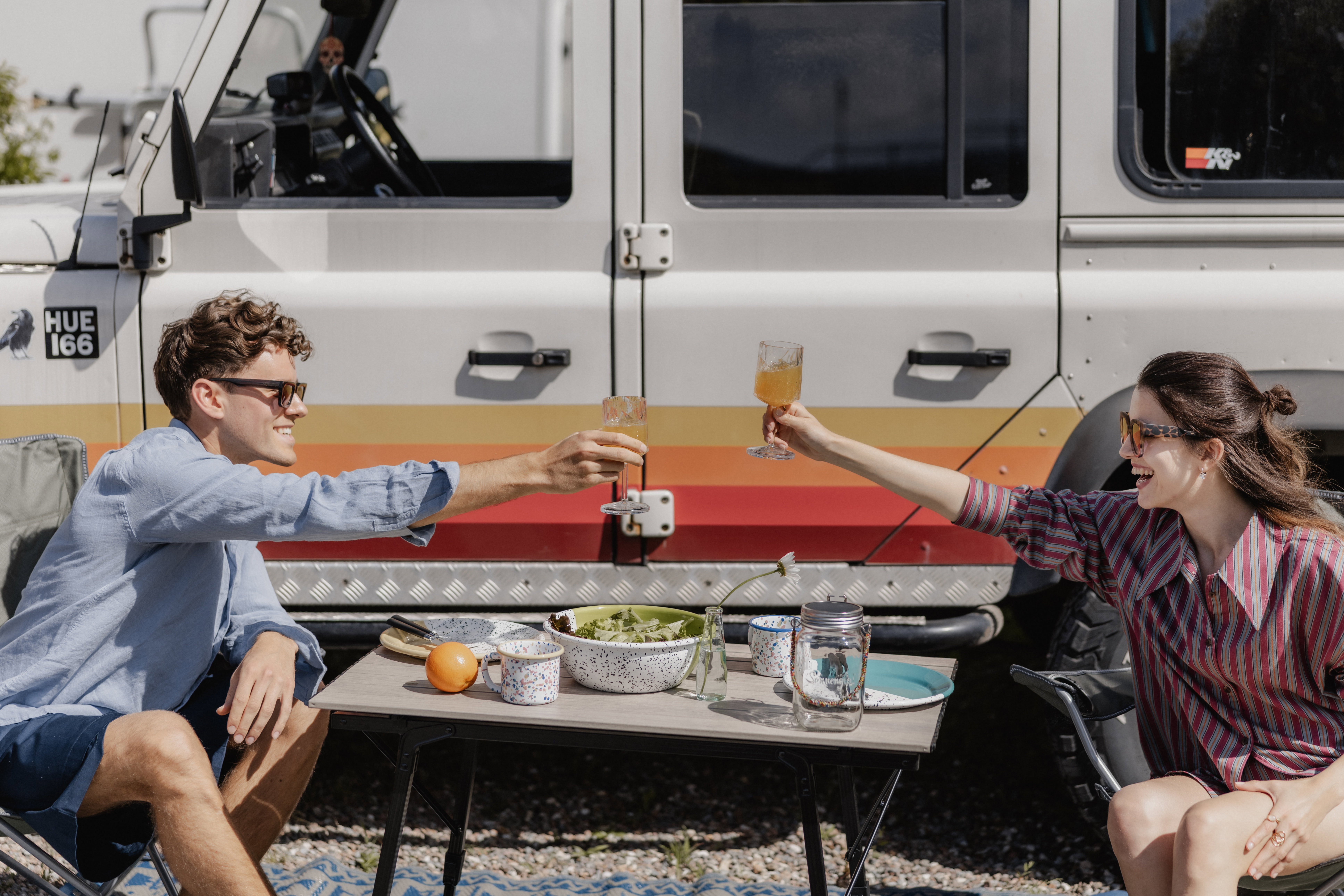 Coppia che beve un caffè accanto a un Land Rover Defender sulle Dolomiti