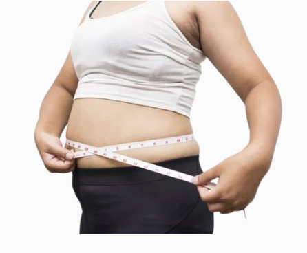 Person in white tank top measuring waist with a tape measure against a white background.
