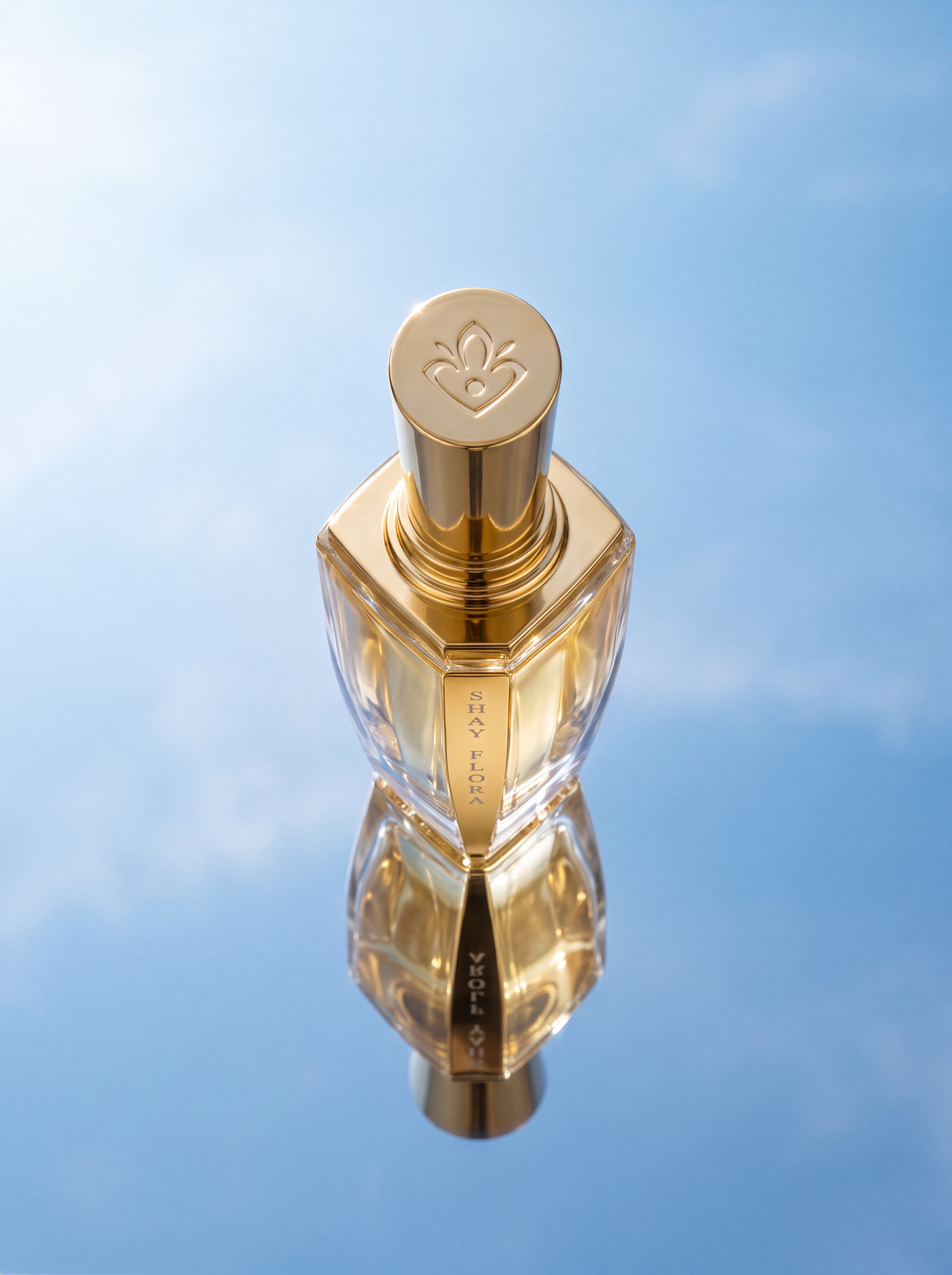 Gold perfume bottle on reflective surface with blue sky background