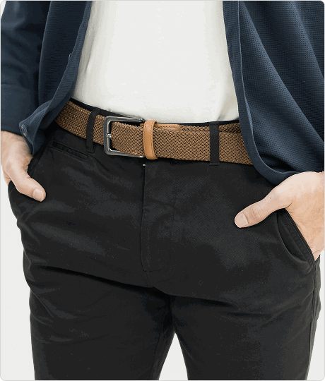 Man in navy blazer and white shirt with hands in black pants pockets, wearing brown woven belt.