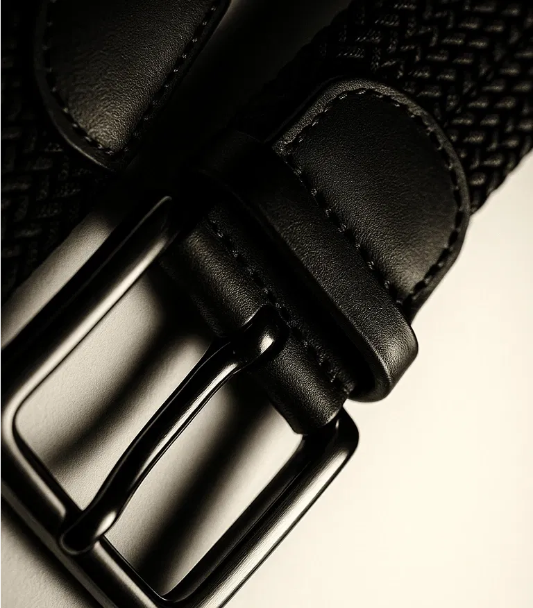 Close-up of a black woven belt buckle on a light surface.