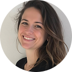 Smiling woman with long brown hair wearing a black top against a plain background.