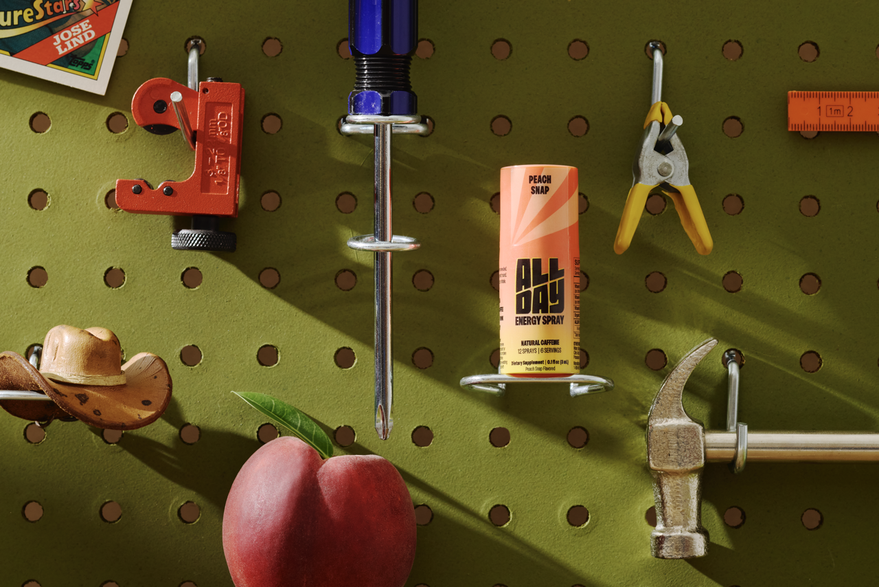 Pegboard with various tools and a can of All Day energy spray in peach snap flavor.