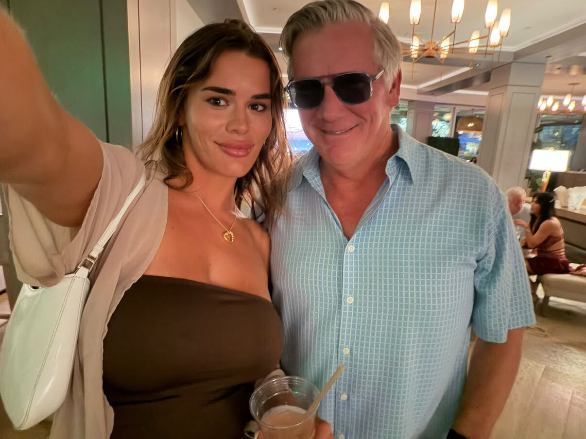 Evening selfie in a hotel lounge of a smiling man in a light blue checked shirt wearing St Barts Sterling Polarised sunglasses, next to a woman