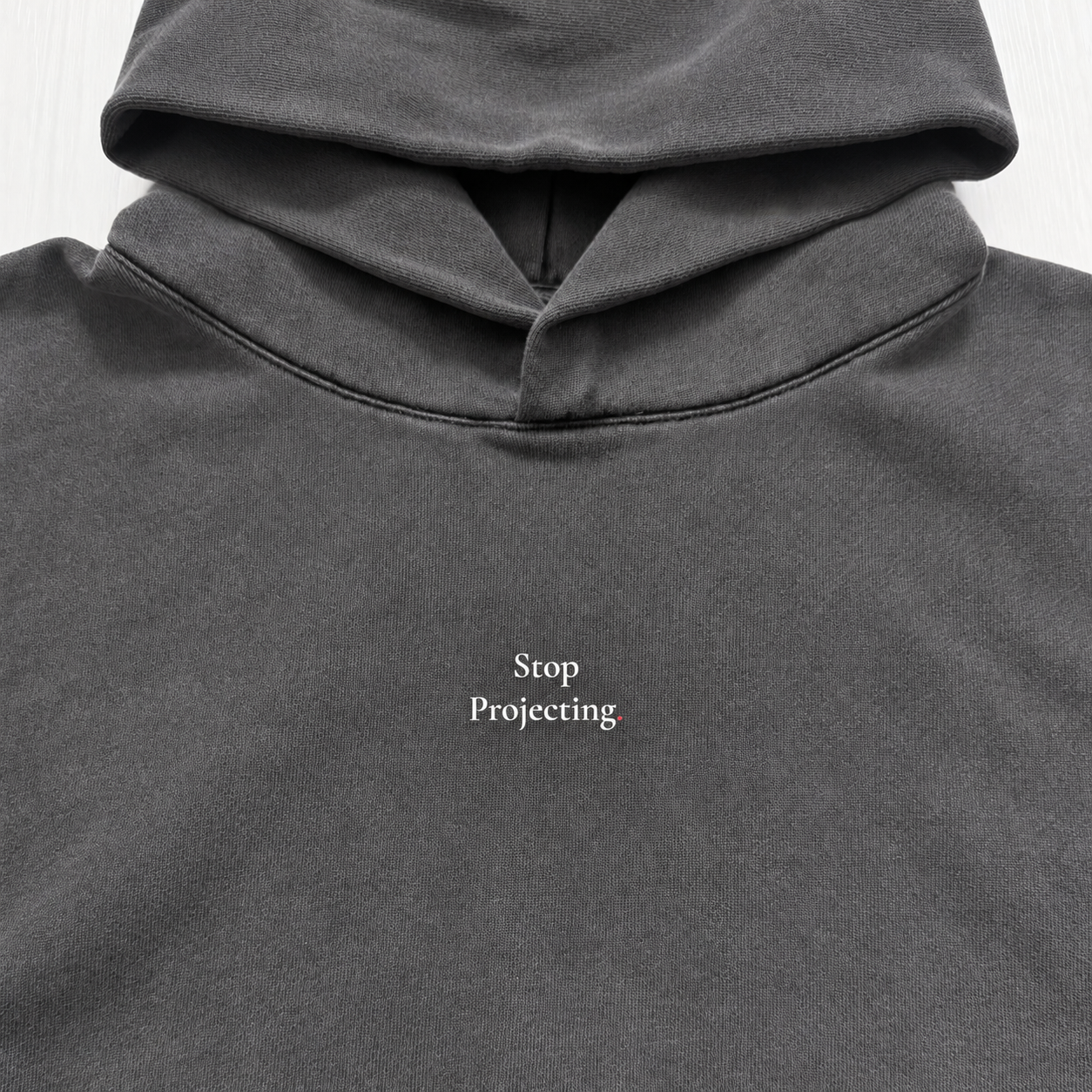 Close-up of the Opps Hoodie front in washed charcoal fleece, showing the small "Stop Projecting." serif chest print below the double-layer hood