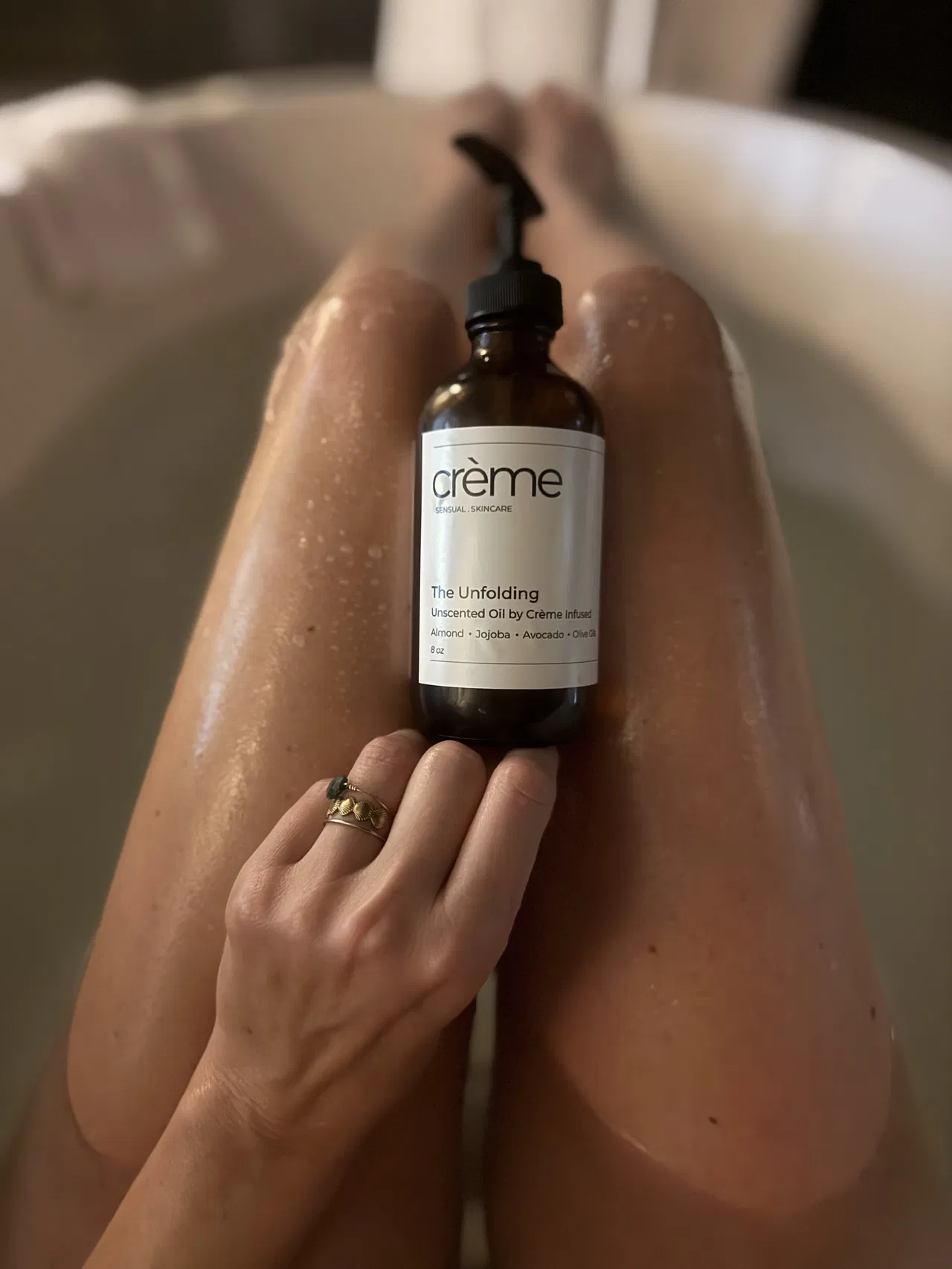 The Unfolding Oil unscented body oil bottle on wet skin showing quick absorption for hormonal skin changes