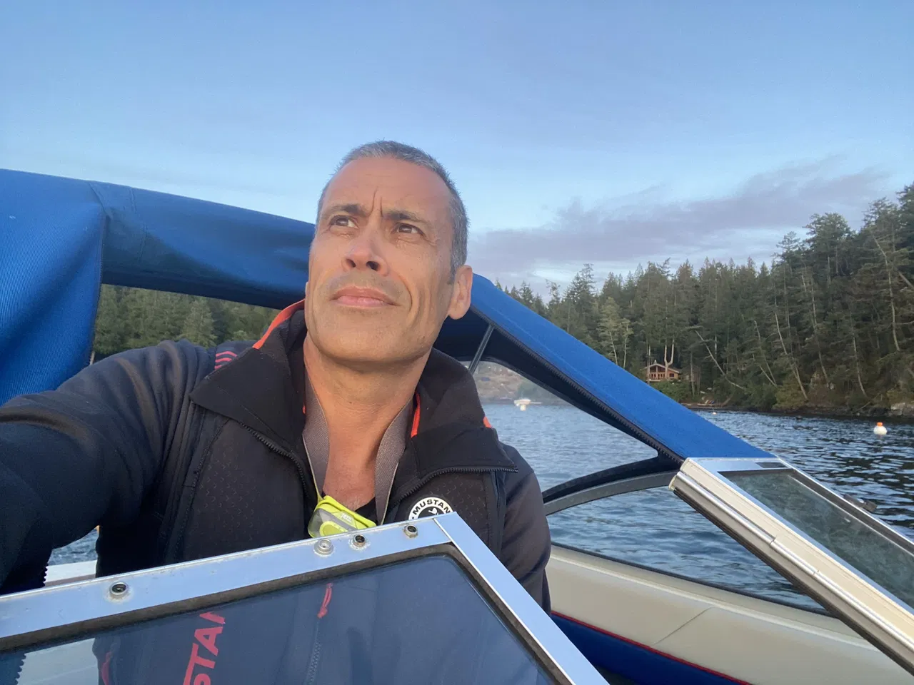 Rolf (Co-founder of Crème) wearing a life jacket on a boat, with a forested shoreline in the background during daylight.