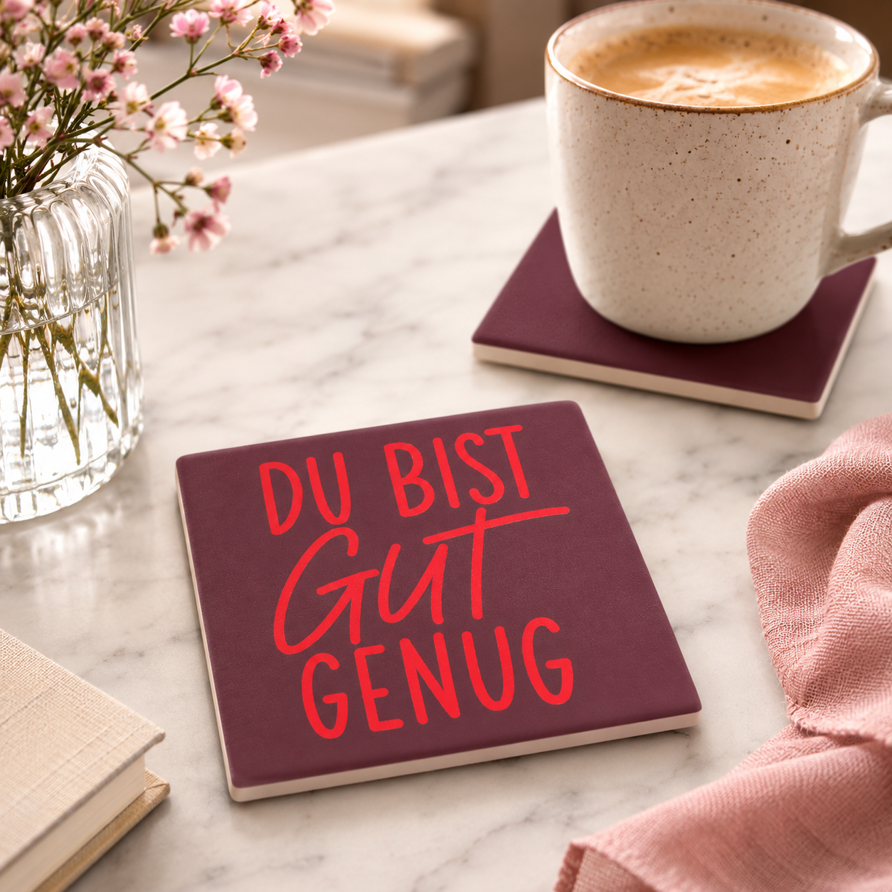 Bedruckte Fliese als Untersetzer mit dem Spruch „Du bist gut genug“ auf einem Marmortisch neben einer Kaffeetasse und frischen Blumen.