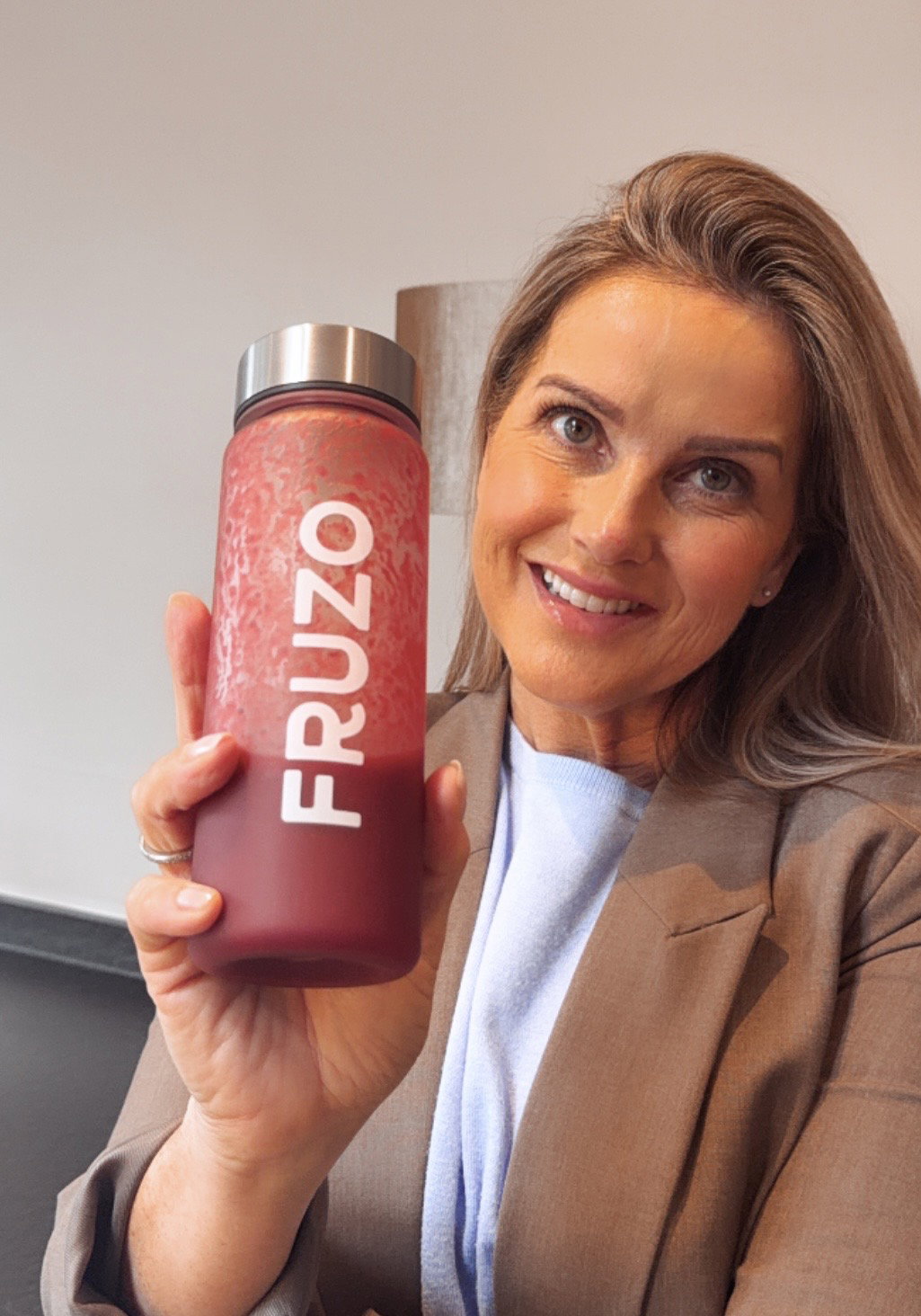 Moeder met twee kinderen die allemaal een fles kleurige smoothie vasthouden