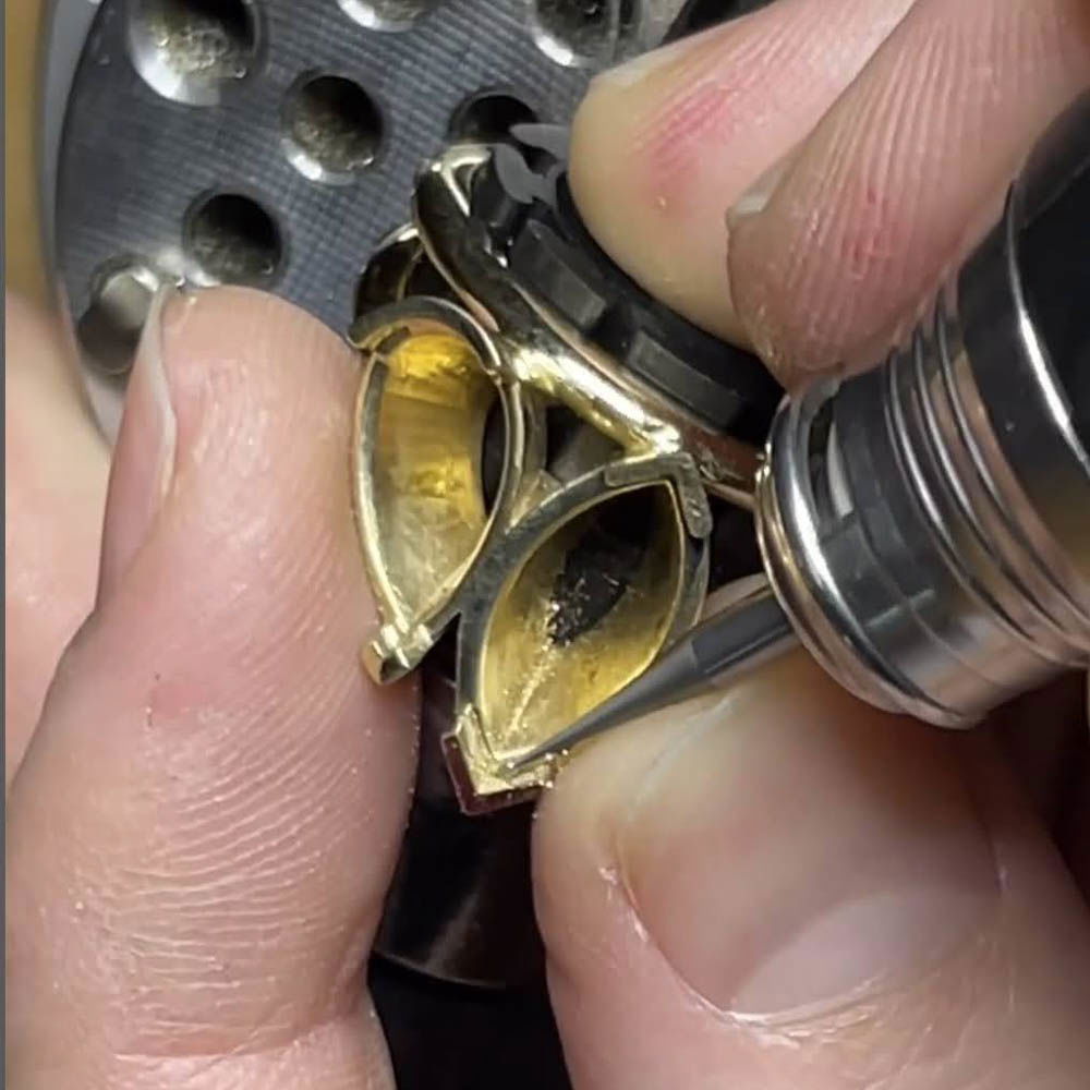Close-up of a jeweler hand-engraving a marquise-shaped gold ring setting at a Lancaster, PA custom jewelry studio.