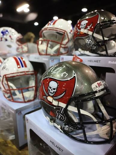 An athlete signing a white football helmet with a black marker at a signing event
