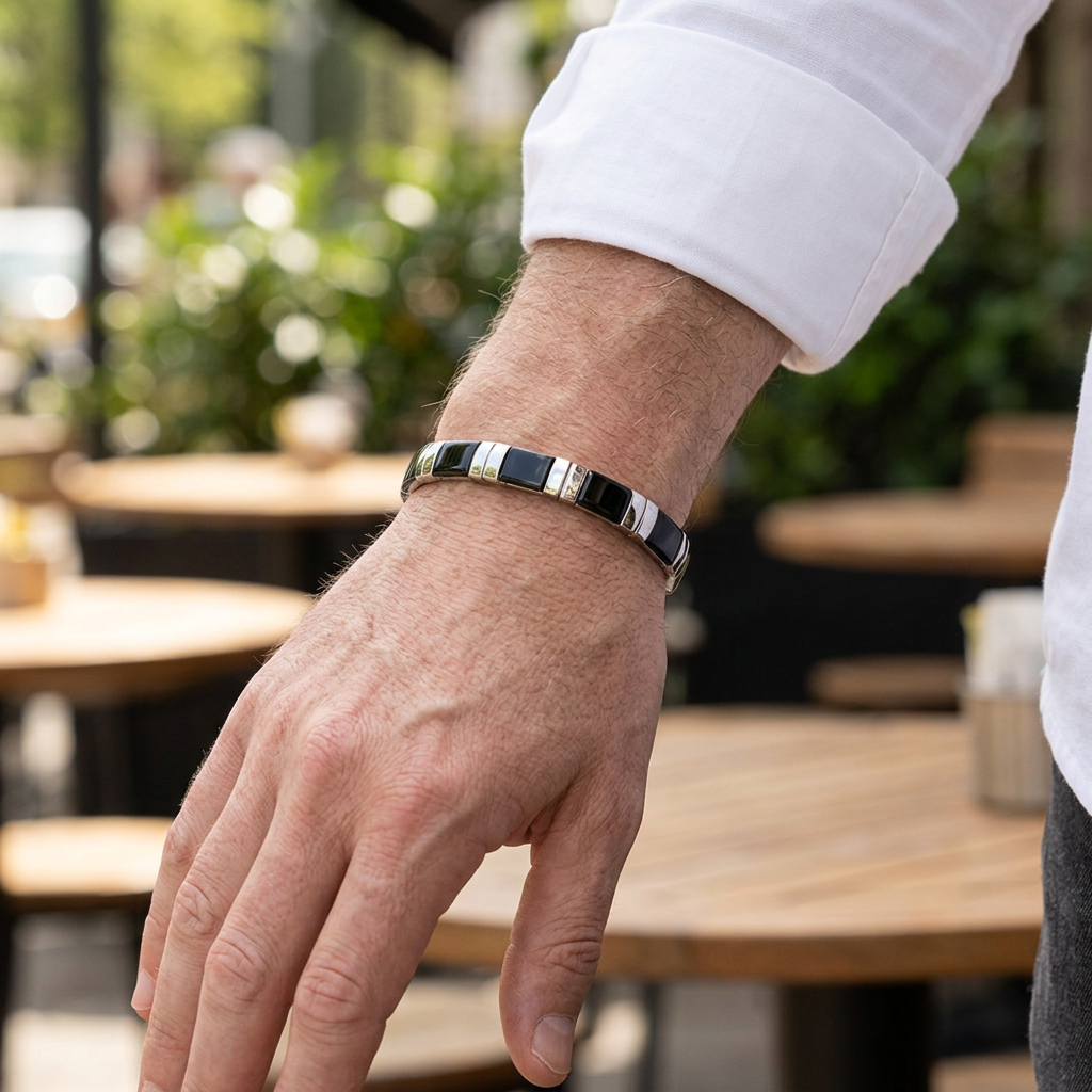 Close-up of a man's hand wearing a black and silver bracelet outdoors