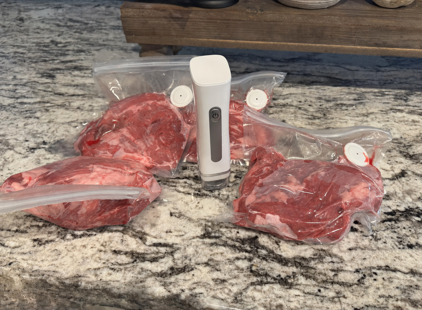 Four cuts of beef vacuum sealed around the handheld sealer