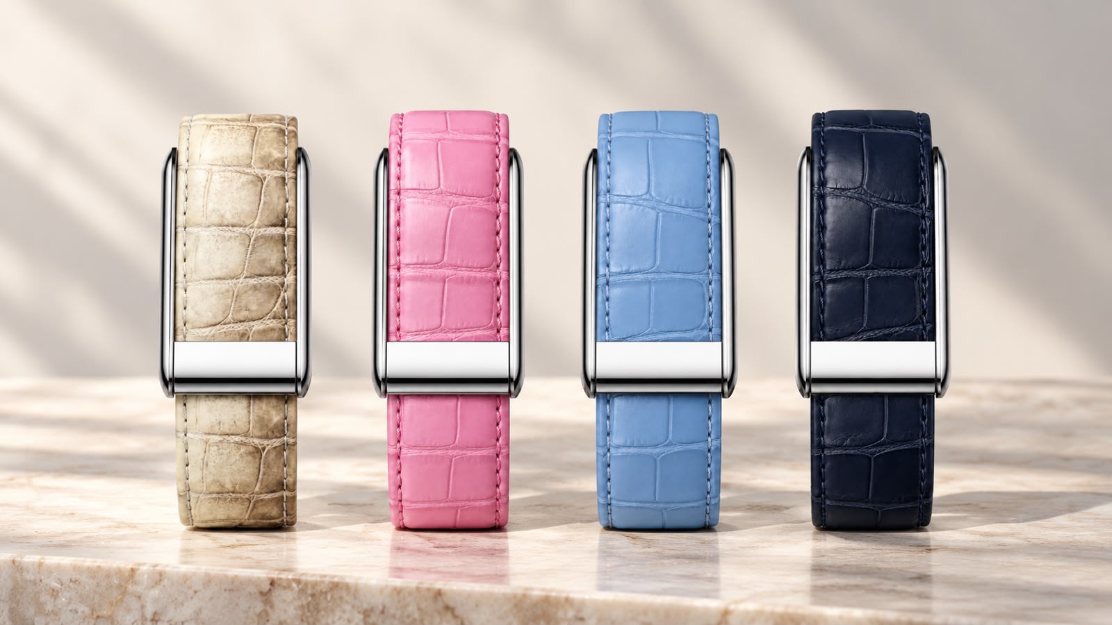 The four 1OF1 crocodile-textured straps in Himalayan, Pink, Ice Blue and Navy, with polished stainless steel clasps, standing on a marble ledge in soft sunlight
