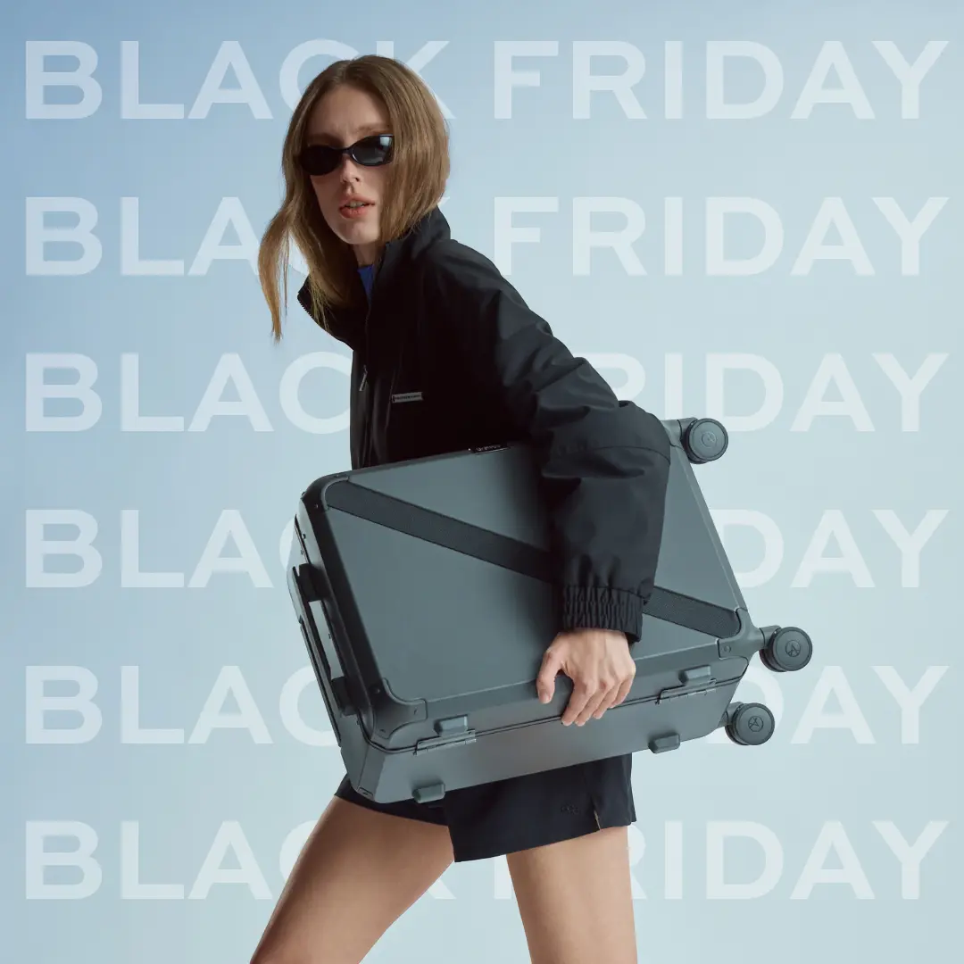 Woman in black with sunglasses carrying an anthracite ARMOIR Cabin Trunk