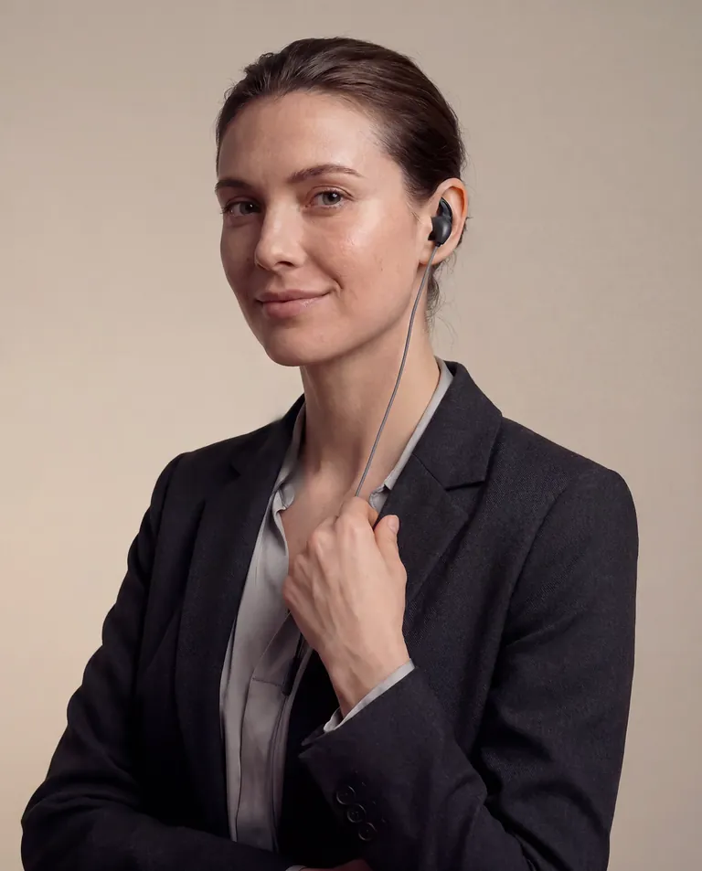 Business woman using an ear-based wellness device for stress relief