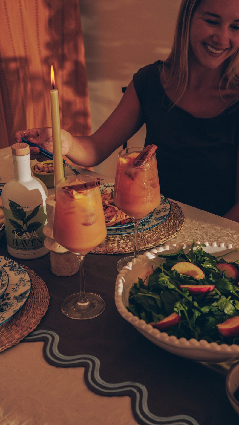 Two friends toasting citrus Kava Haven mocktails over a sunny pool