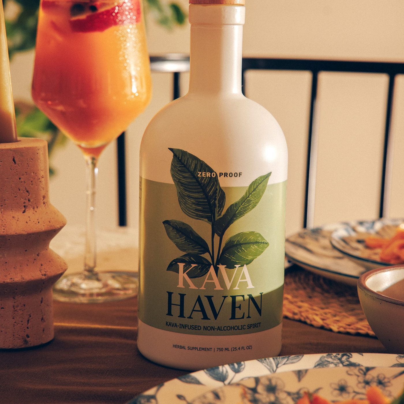 Kava Haven bottle on a candlelit dinner table beside a citrus spritz