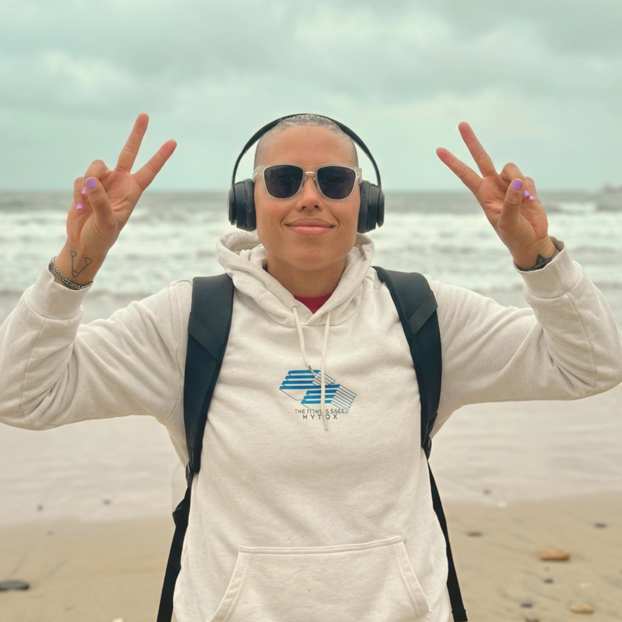 Customer flashing peace signs on the shoreline wearing clear-framed H2OAthletics sunglasses