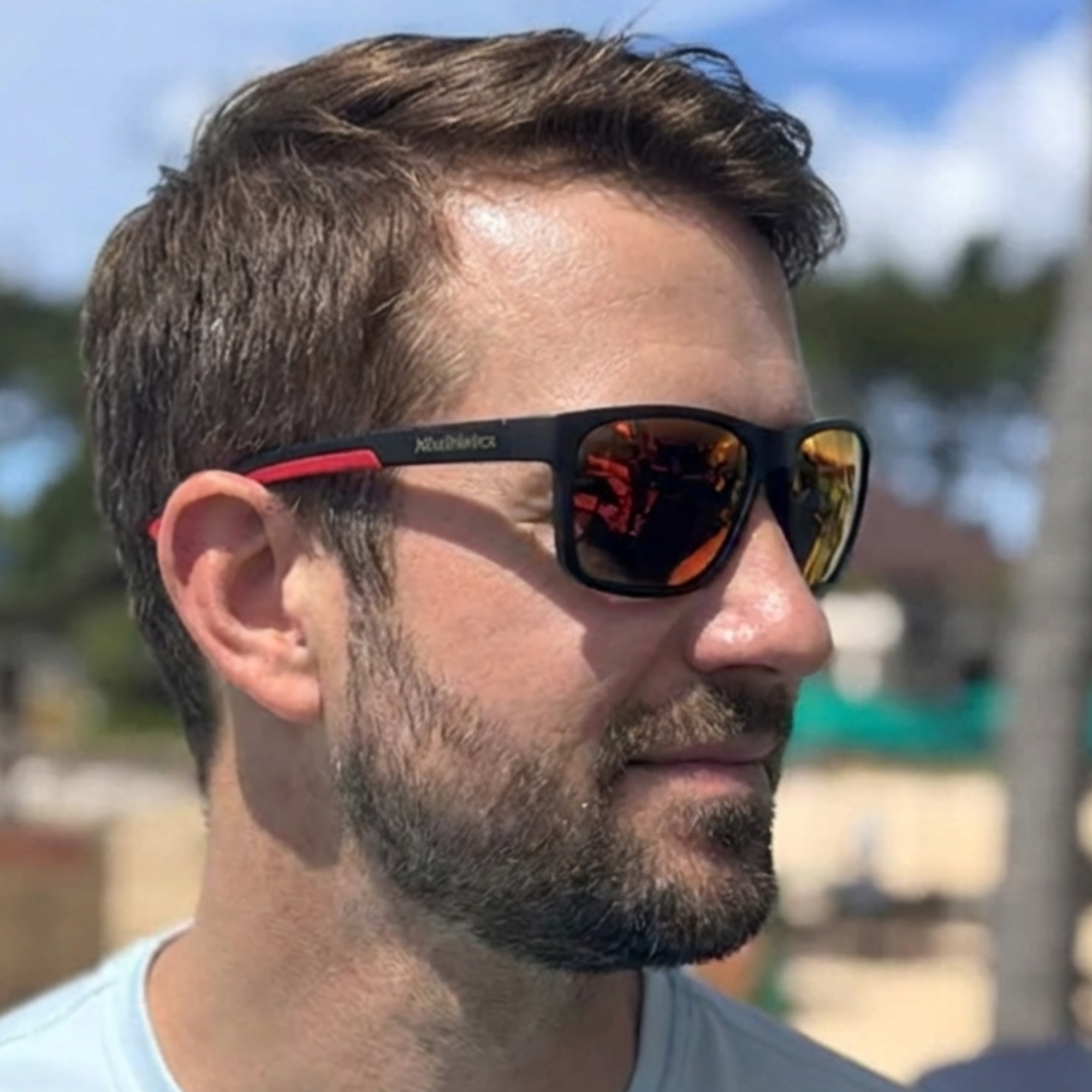 Customer in profile on a sunny day wearing black H2OAthletics sunglasses with red temple tips and orange mirror lenses