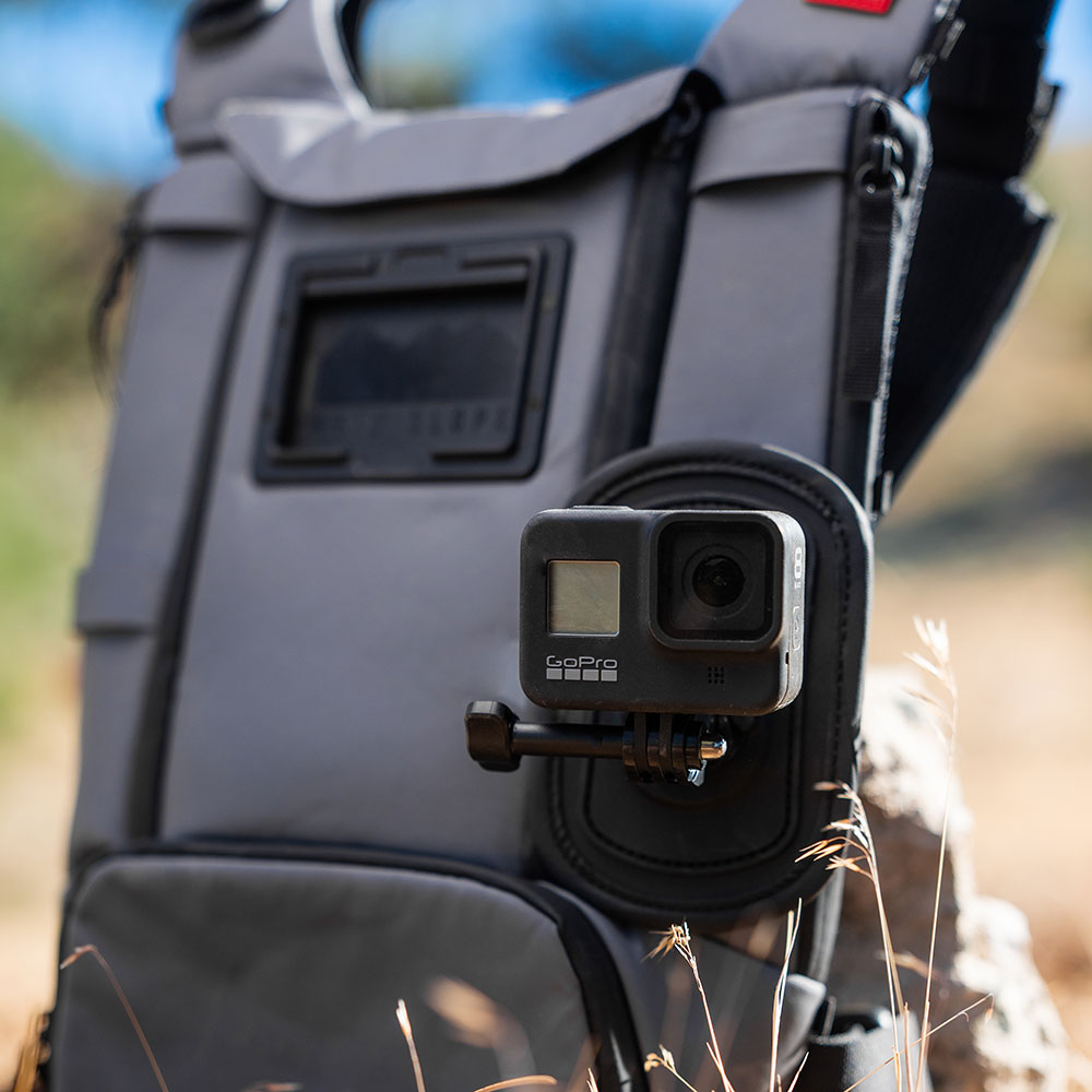 Action camera mounted on the Action Camera Kit plate on the front of a grey West Slope chest pack, beside the phone window