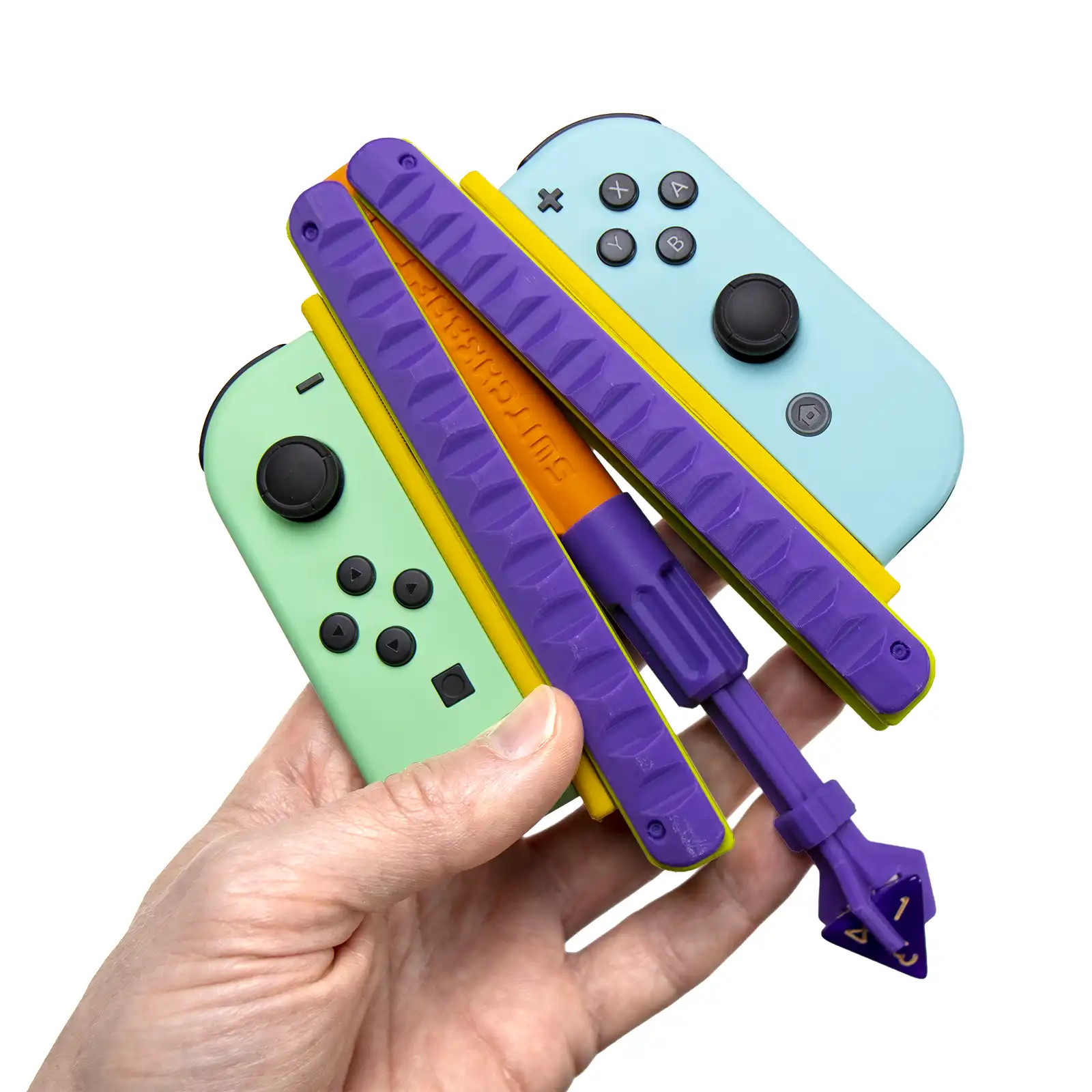 Joycon Adapter in hand: a mint and a sky blue Joy-Con mounted on a purple and orange kARTIFACT with a purple d4 die