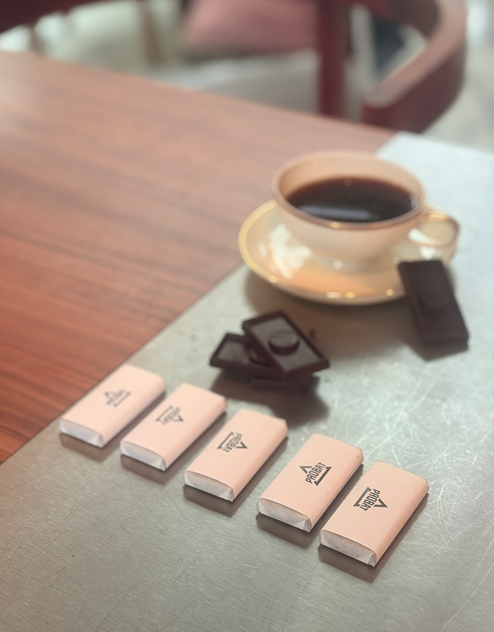 CHOCQLATE Mini-Schokoladen auf einem Tisch neben einer Tasse Kaffee