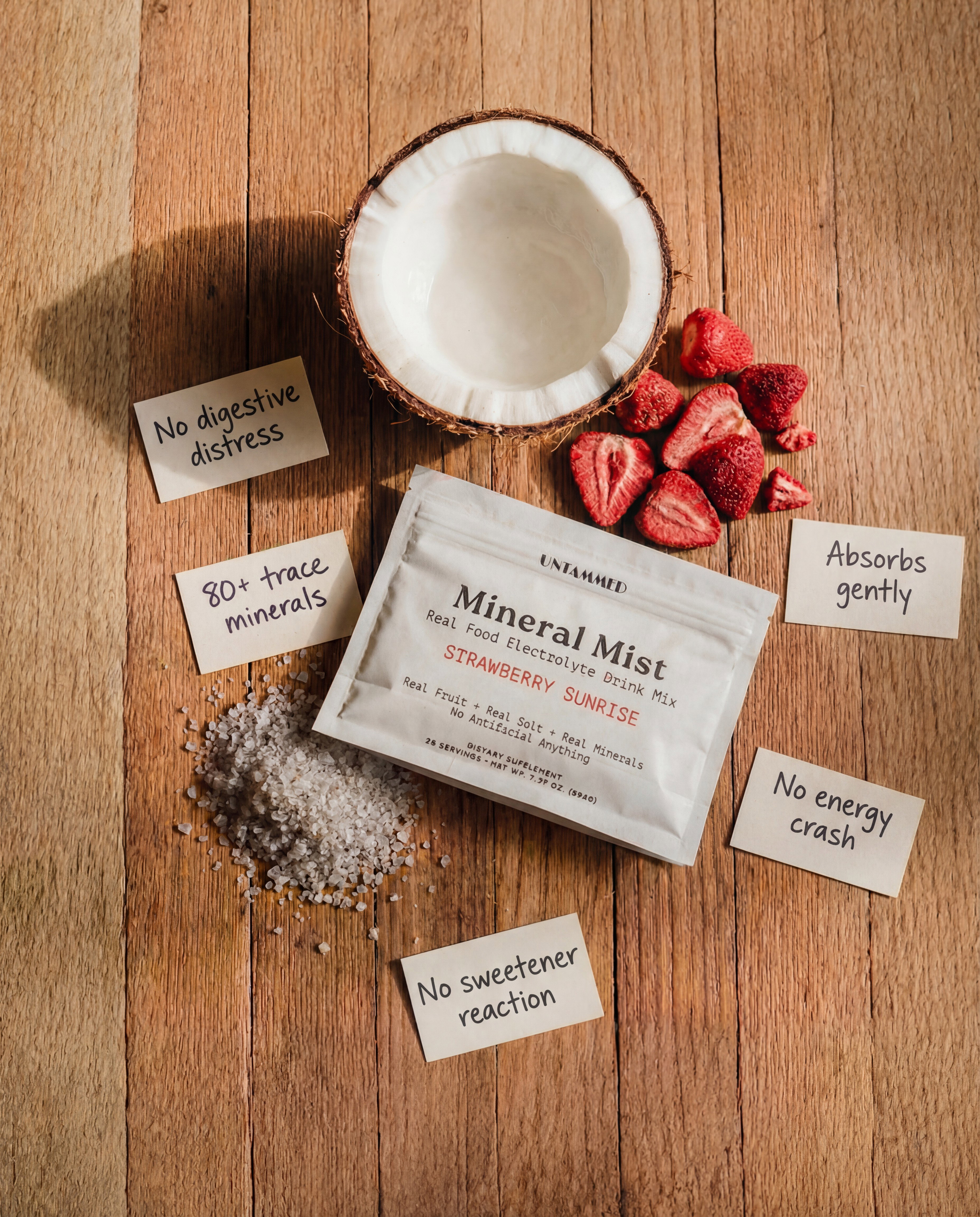 Mineral Mist Strawberry Sunrise pouch on a wooden table with coconut, dried strawberries and sea salt