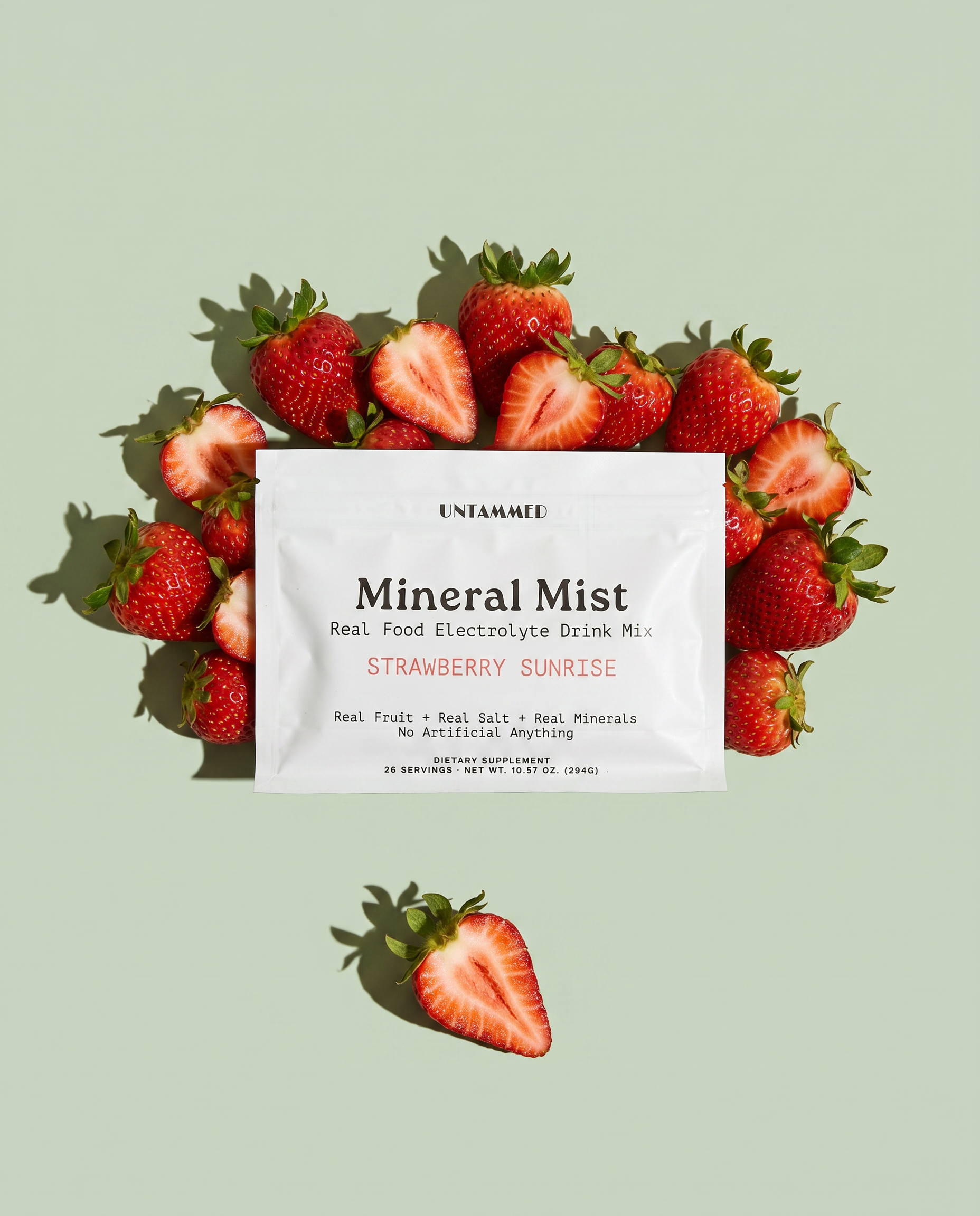 Mineral Mist Strawberry Sunrise pouch surrounded by fresh strawberries on a sage green background