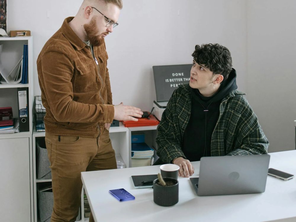 Two colleagues talking at a desk, with Pocket on the desk