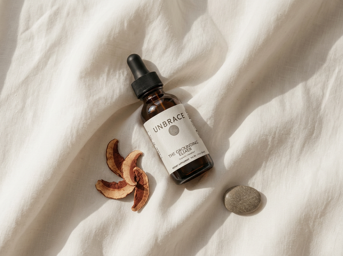 The amber dropper bottle on linen beside dried reishi slices in raking morning light