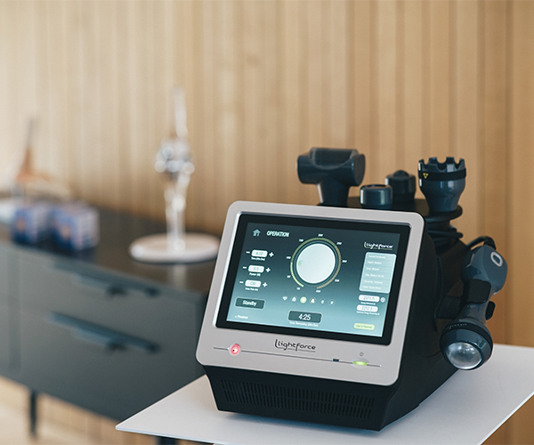 Appareil thérapeutique doté d'un écran tactile et de plusieurs applicateurs, posé sur une table d'appoint dans un cabinet moderne