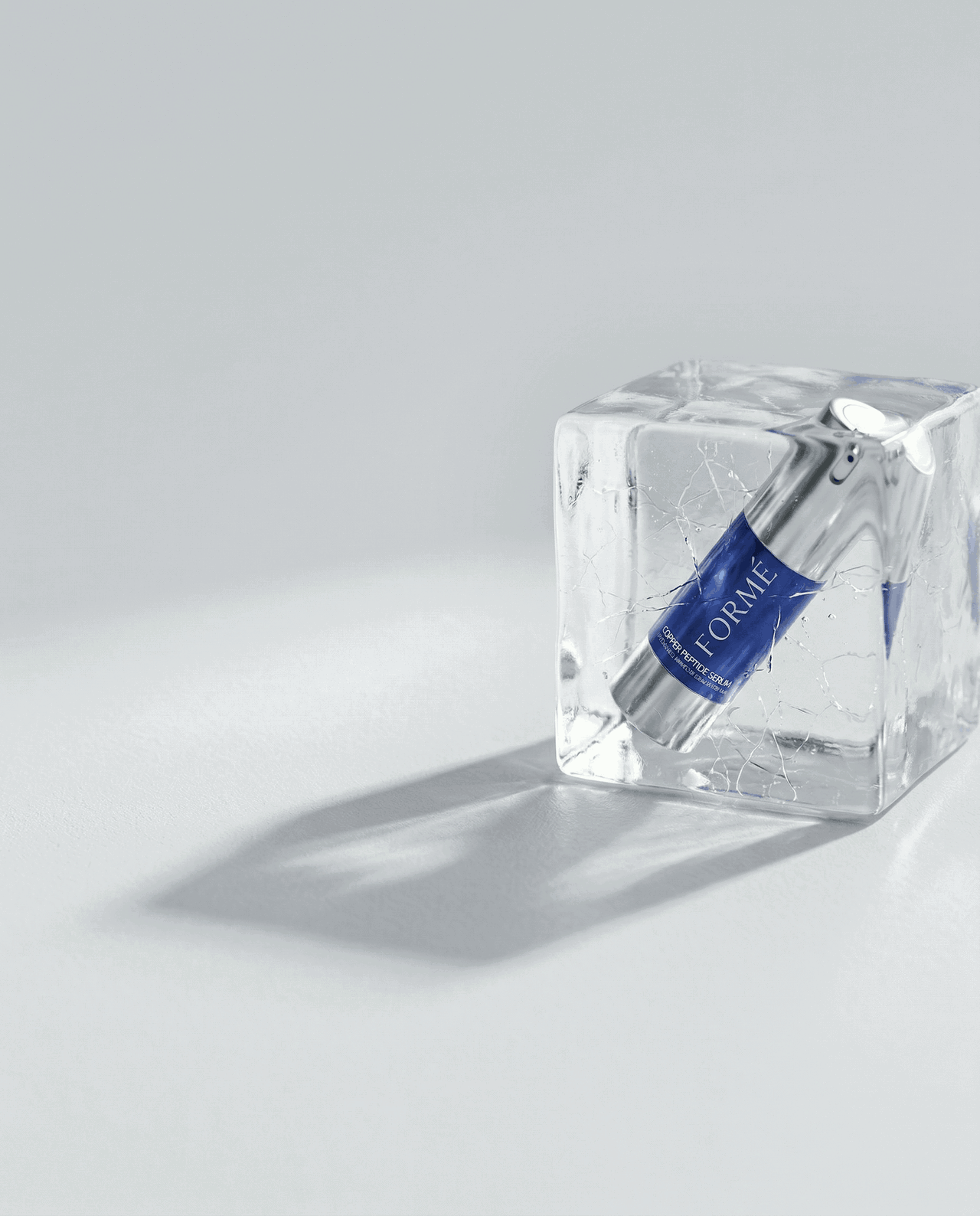 Formé copper peptide serum bottle in ice representing stable skincare formula