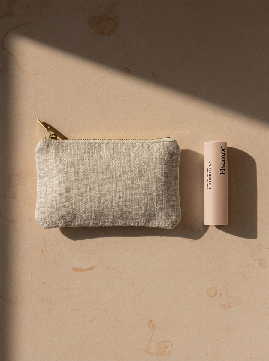 Beige fabric pouch with gold zipper next to a cylindrical lip balm on a marble surface