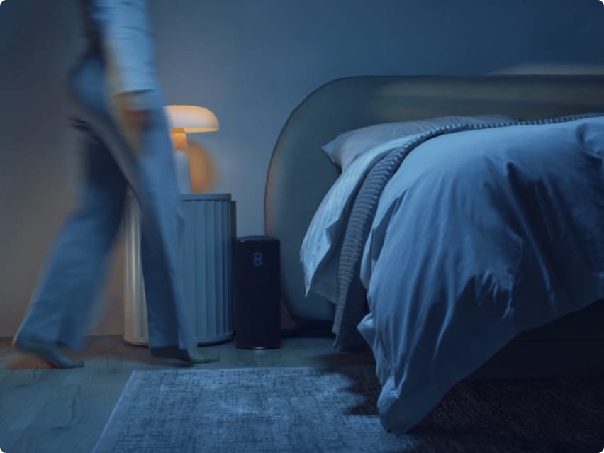 Calm, dark bedroom with a cozy bed as someone heads to sleep