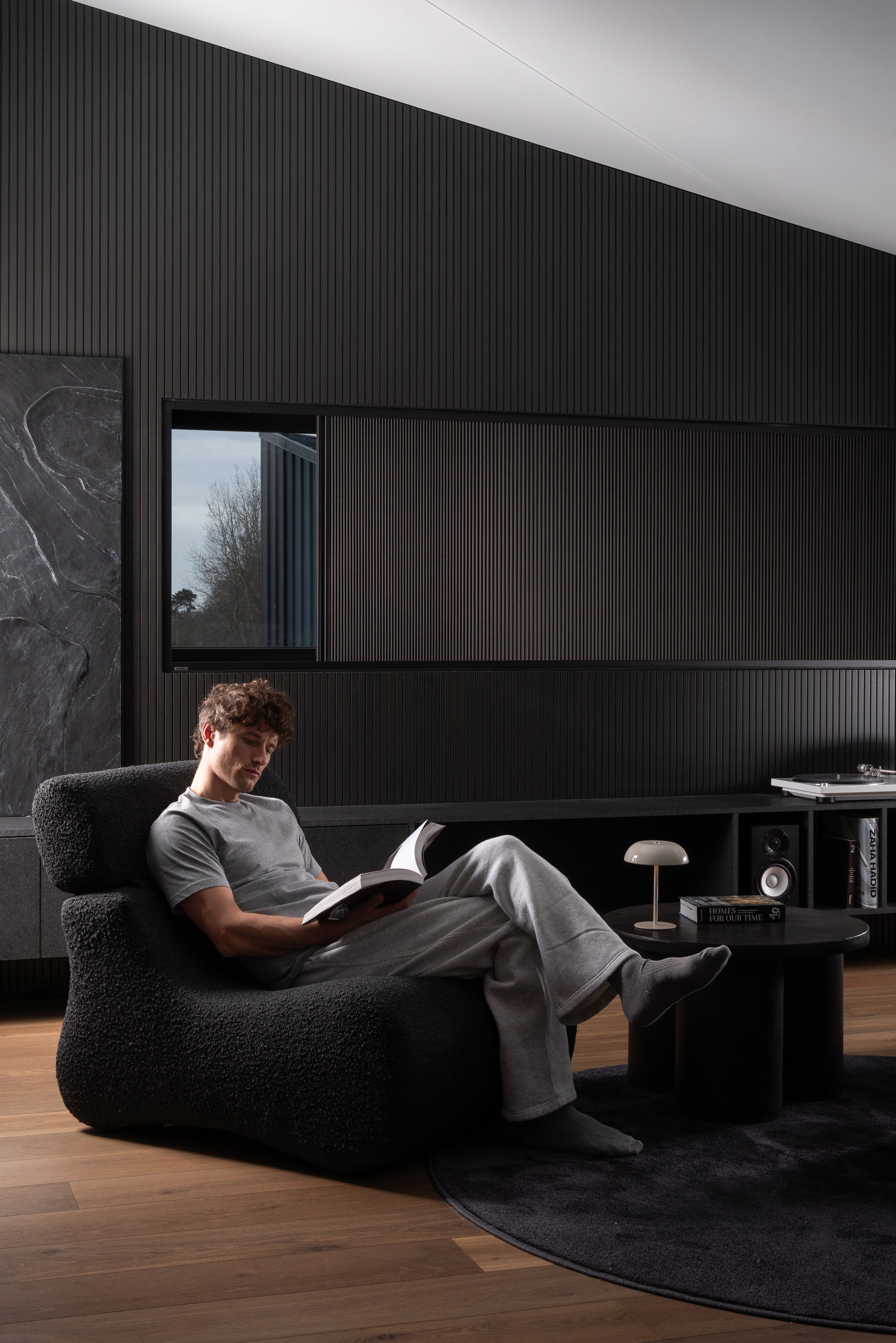 Man reading in a lounge chair in a dark room with a Guard blackout blind on the window