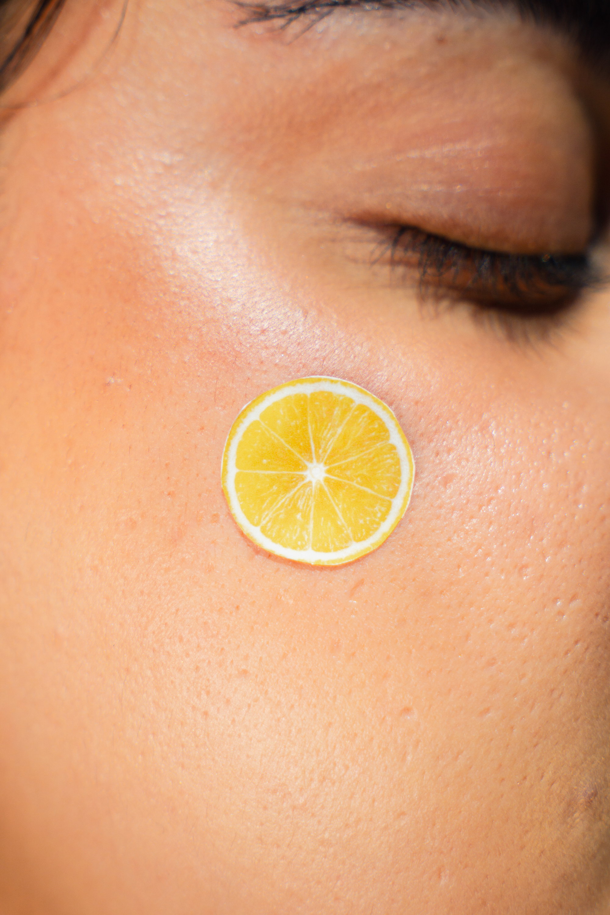 Woman with dewy skin holding the Lemon Jelly cleanser beside her cheek