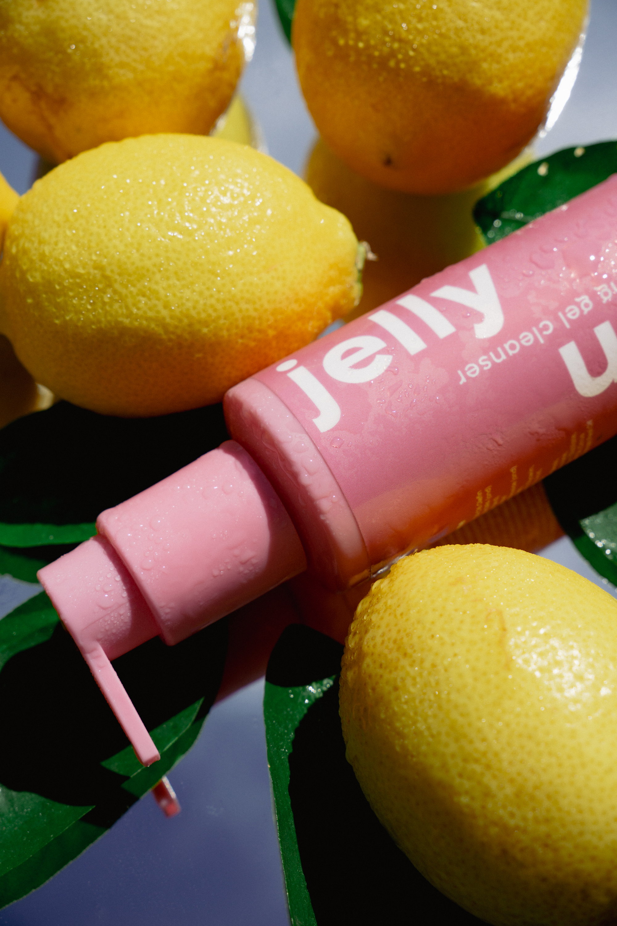 Lemon Jelly cleanser bottle with fresh citrus on a glossy surface