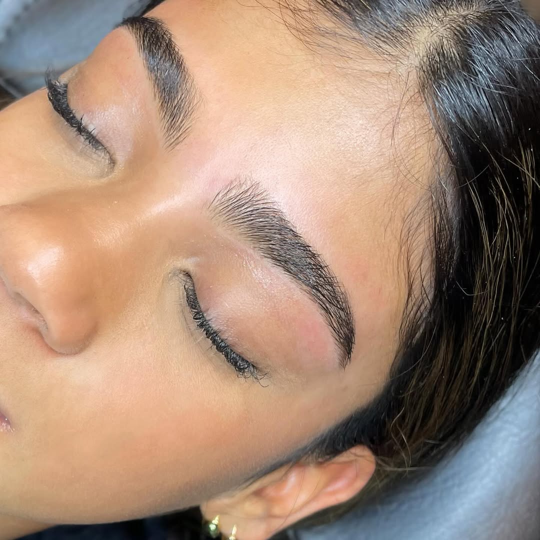 Close-up of a person's face with neatly groomed eyebrows and closed eyes.