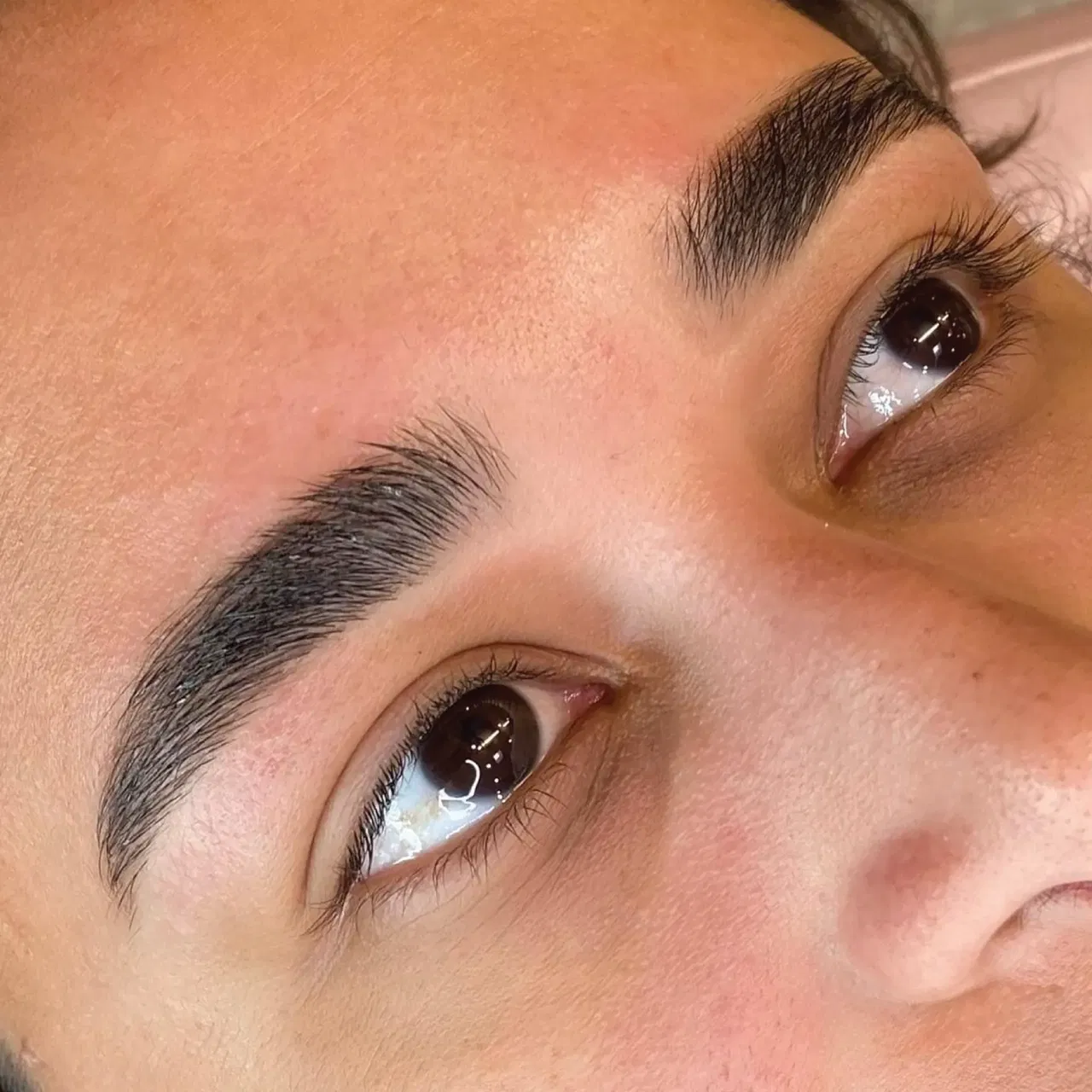 Close-up of a person's face showing well-groomed, shaped eyebrows and clear skin.